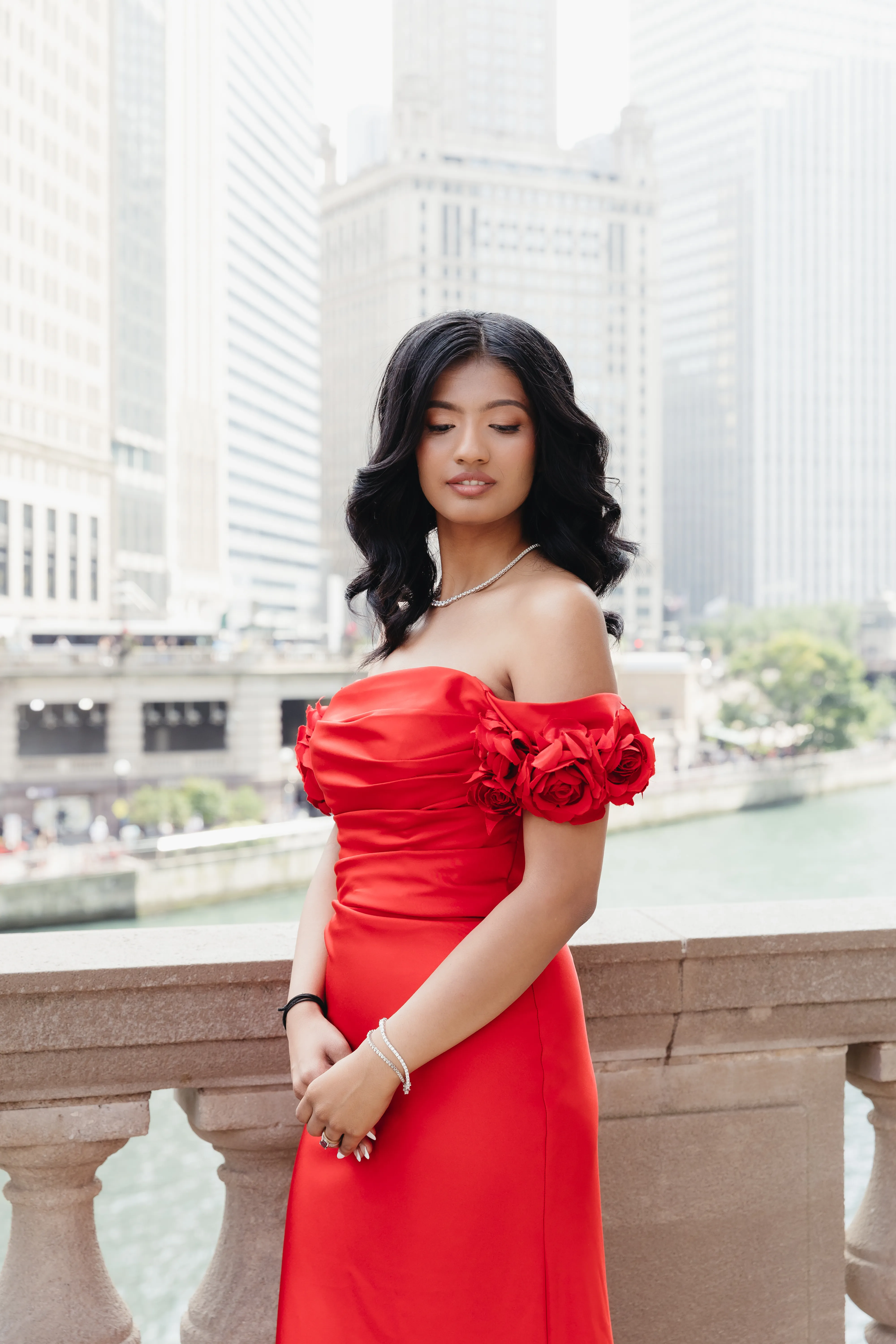 Bride in a red gown with soft glam makeup and dark waves beside the Chicago River