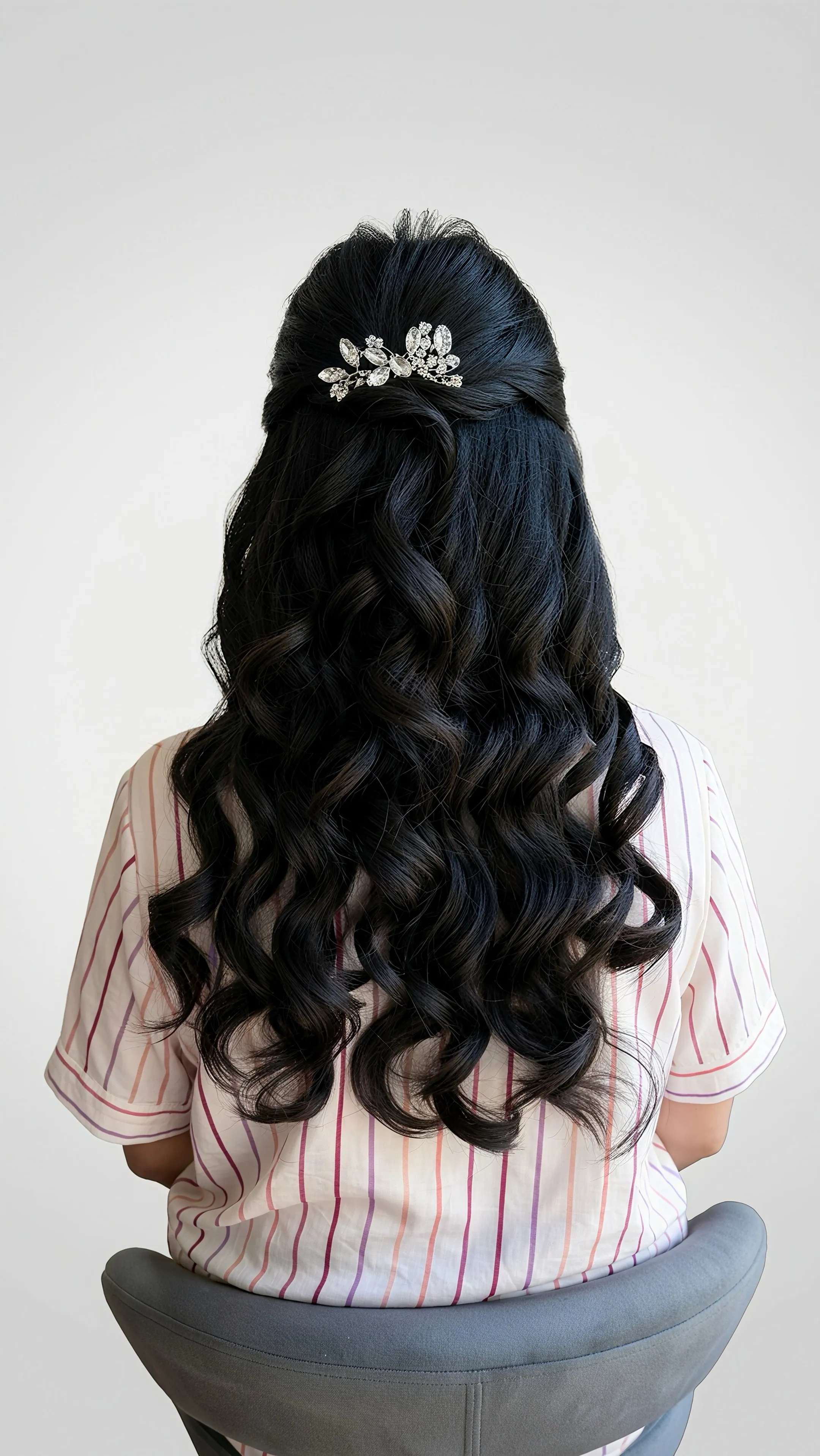 Full view of a romantic half-up event hairstyle with cascading curls and a jeweled hair accessory