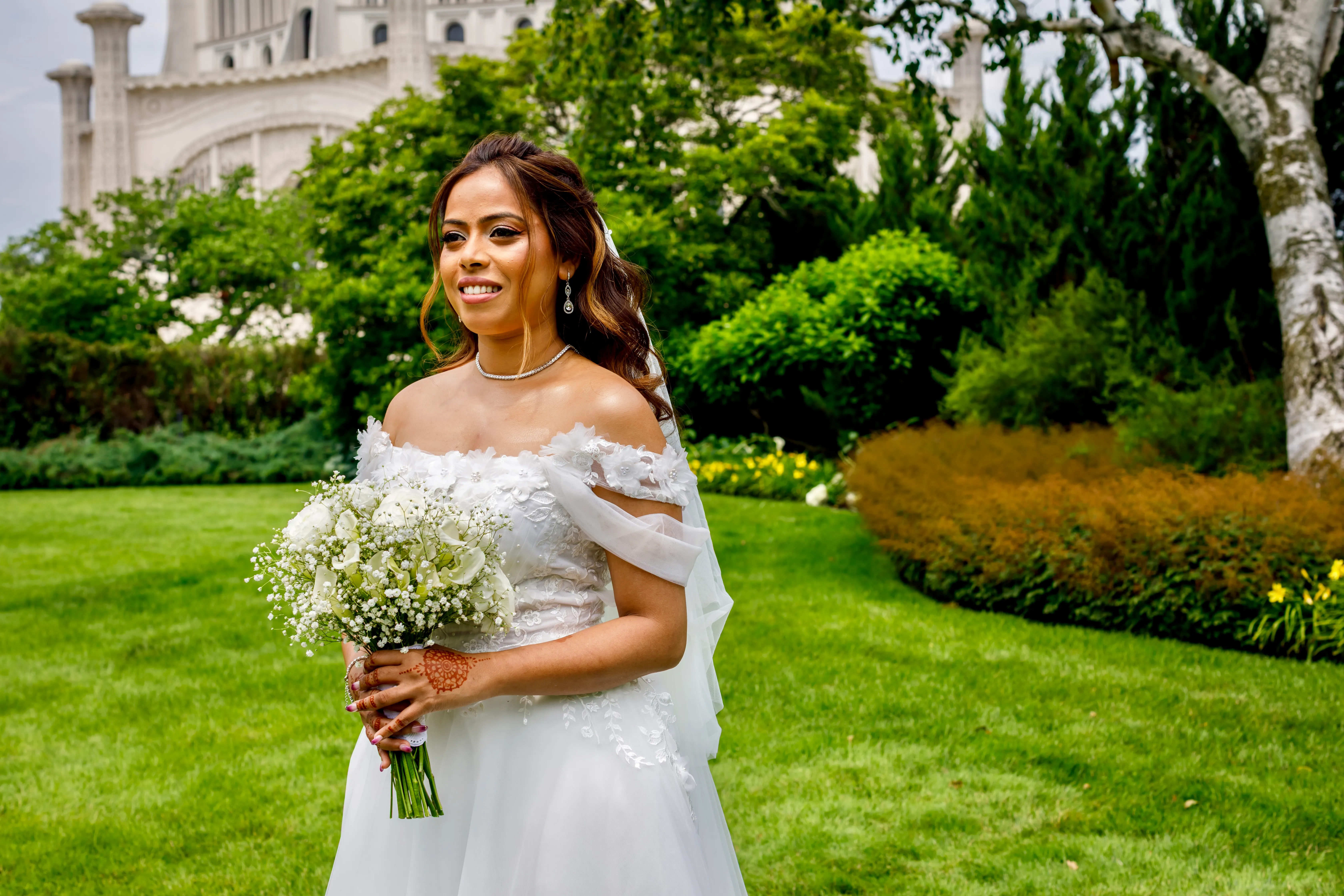 Bride with soft glam makeup and romantic waves holding a white bouquet outdoors